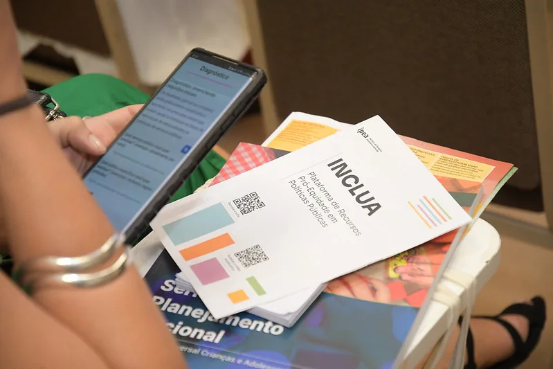Guias metodológicos e materiais impressos do projeto INCLUA dispostos sobre uma mesa.