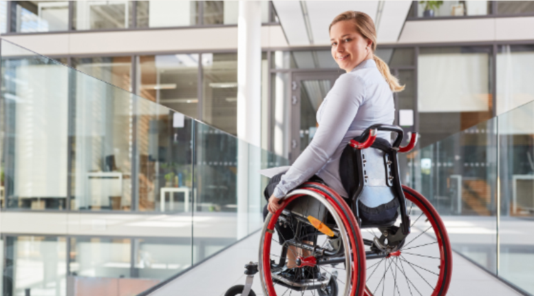 Imagem de mulher branca, cabelo liso, alegra e saudável, em uma cadeira de rodas.